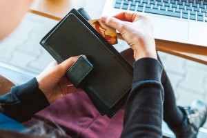 female holding a wallet with credit cards near a laptop computer